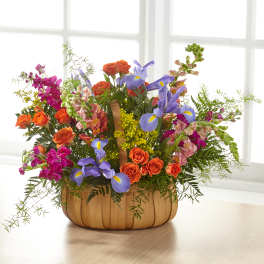 Mixed bouquet of orange roses, purple irises, and pink snapdragons in a wooden basket