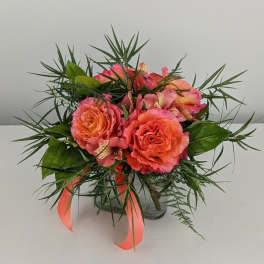 Coral roses and pink alstroemeria in a glass vase with ribbon