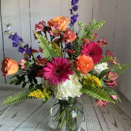Mixed bouquet in a glass vase with pink gerberas, orange roses, and white hydrangea