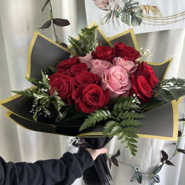 Bouquet of red and pink roses wrapped in black paper with gold trim