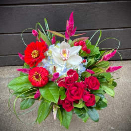 Bouquet of red roses, white orchid, and red zinnias with pink accents