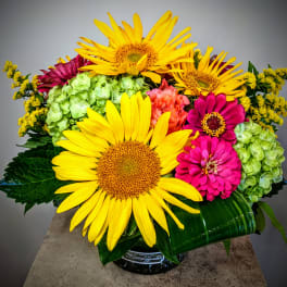 Bright bouquet with sunflowers, zinnias, and hydrangeas in a glass vase