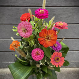 Bright zinnia bouquet in a glass vase with mixed pink, orange, and purple blooms