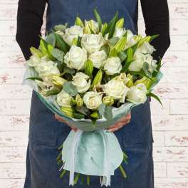 Bouquet of white roses and lily buds wrapped in pale mint paper