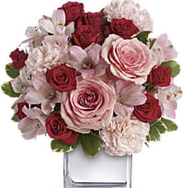Pink and red roses with pale pink flowers in a clear glass vase