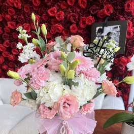 Pink and white bouquet in a clear vase with a birthday topper