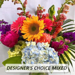 Bright mixed flower arrangement with sunflower, pink gerbera, roses and hydrangeas in a clear glass vase