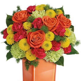 Orange roses and mixed flowers in an orange glass vase