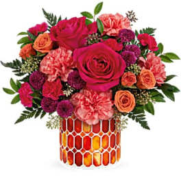 Bouquet of pink and orange roses in a patterned glass vase