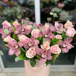 Pink roses and orchids arranged in a blush hatbox