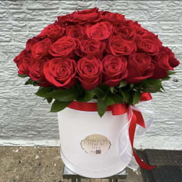 Red roses arranged in a white hat box with a red ribbon
