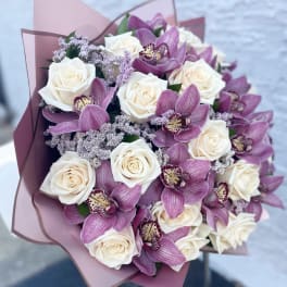 Bouquet of white roses and purple orchids wrapped in pink paper