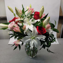 Bouquet of red and pink roses with white lilies in a glass vase