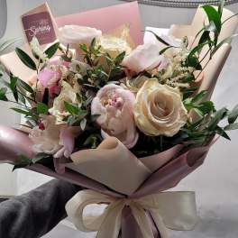 Bouquet of pale pink and cream roses wrapped in pink paper with a ribbon