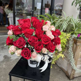 Large bouquet of red and pale pink roses in a white hatbox