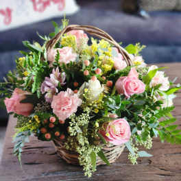Pink roses and carnations in a wicker basket
