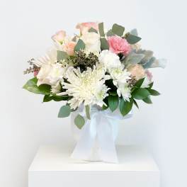 Bouquet of white and blush flowers in a white vase with a ribbon