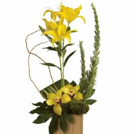 Yellow lilies and orchids arranged in a wooden container