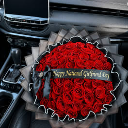 Large bouquet of red roses with a black ribbon and gift banner in a car seat