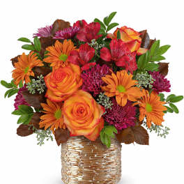 Orange roses and magenta daisies in a gold-textured vase