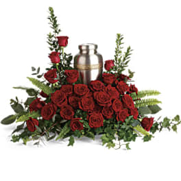 Red roses arranged around a silver urn with greenery