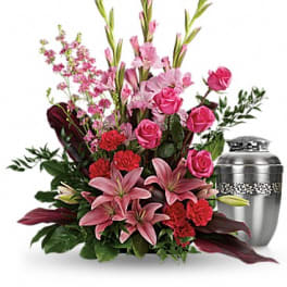 Pink lilies and roses arranged beside a silver urn.