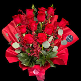 Bouquet of red roses wrapped in red paper with greenery