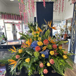 Large tropical floral arrangement with birds of paradise, roses, hydrangeas, and greenery