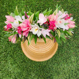 Pink and white floral arrangement in a woven basket