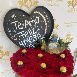 Heart-shaped rose arrangement with a tequila bottle, chocolates, and a chalkboard sign