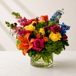 Colorful mixed bouquet in a clear glass vase with roses and lilies