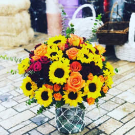 Bouquet of sunflowers and orange roses in a decorative container