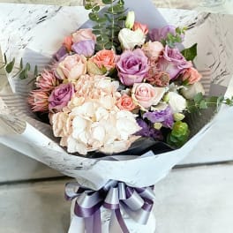 Bouquet of pastel roses and hydrangeas wrapped in white paper