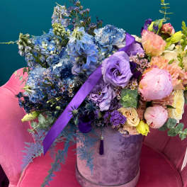 Large mixed bouquet in a lavender hatbox with blue, purple, and pink flowers
