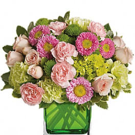 Pink and green mixed flower arrangement in a square glass vase
