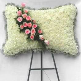 White floral funeral spray with pink roses on an easel