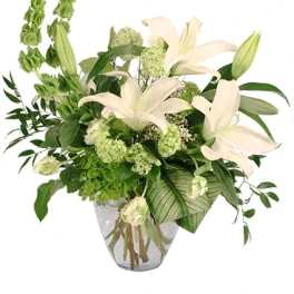 White lilies and green flowers in a clear glass vase