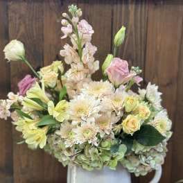 Pastel bouquet in a white pitcher vase with roses, chrysanthemums, and lilies