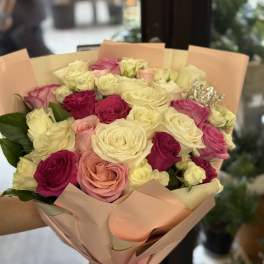 Bouquet of pink, cream, and white roses wrapped in peach paper