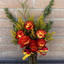 Bouquet of red and yellow roses in a glass vase with a ribbon