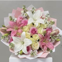 Pink and white bouquet with lilies and roses wrapped in pastel paper