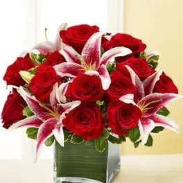 Red roses and pink lilies arranged in a square glass vase