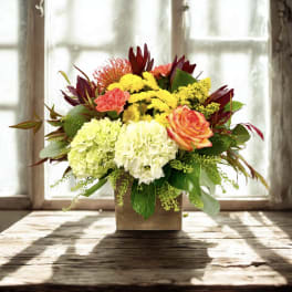 Mixed bouquet in a square wooden vase with hydrangeas, roses, and chrysanthemums