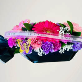 Colorful bouquet with gerbera daisies and carnations wrapped in dark paper