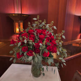 Red rose arrangement in a clear glass vase on a table