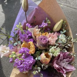 Bouquet of purple, pink, and yellow flowers wrapped in brown and purple paper