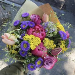 Hand-tied bouquet of pink roses, tulips, and purple daisies