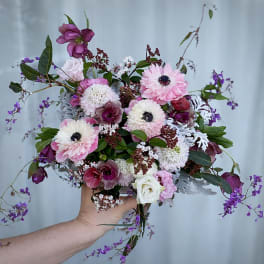 Handheld bouquet of pink, white, and purple flowers