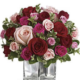 Bouquet of red, pink, and blush roses in a clear glass vase
