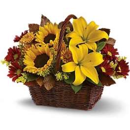 Basket arrangement with yellow lilies, sunflowers, and red daisies
